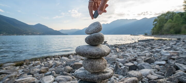 Turm aus Steinen vor See, Bergpanorama