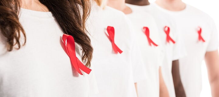 fünf Personen mit weißem T-Shirt und roter Schleife angesteckt