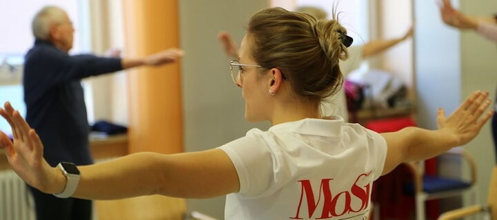 Trainerin aktiv bei Bewegungseinheit mit Seniorengruppe