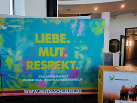 Stellwand zur Ausstellung der Mutmachleute. Schriftzug Liebe. Mut. Respekt. auf buntem Hintergrund